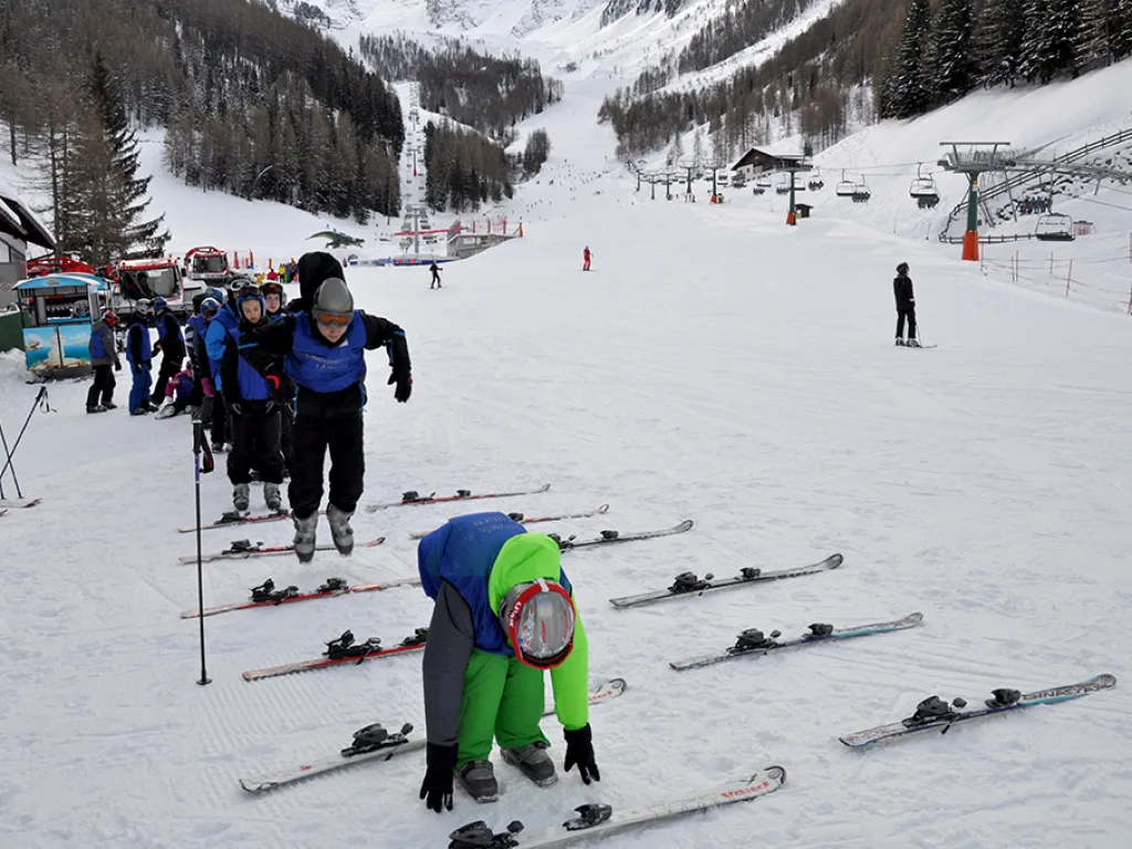 Jugendliche schnallen an der Talstation ihre Ski an.
